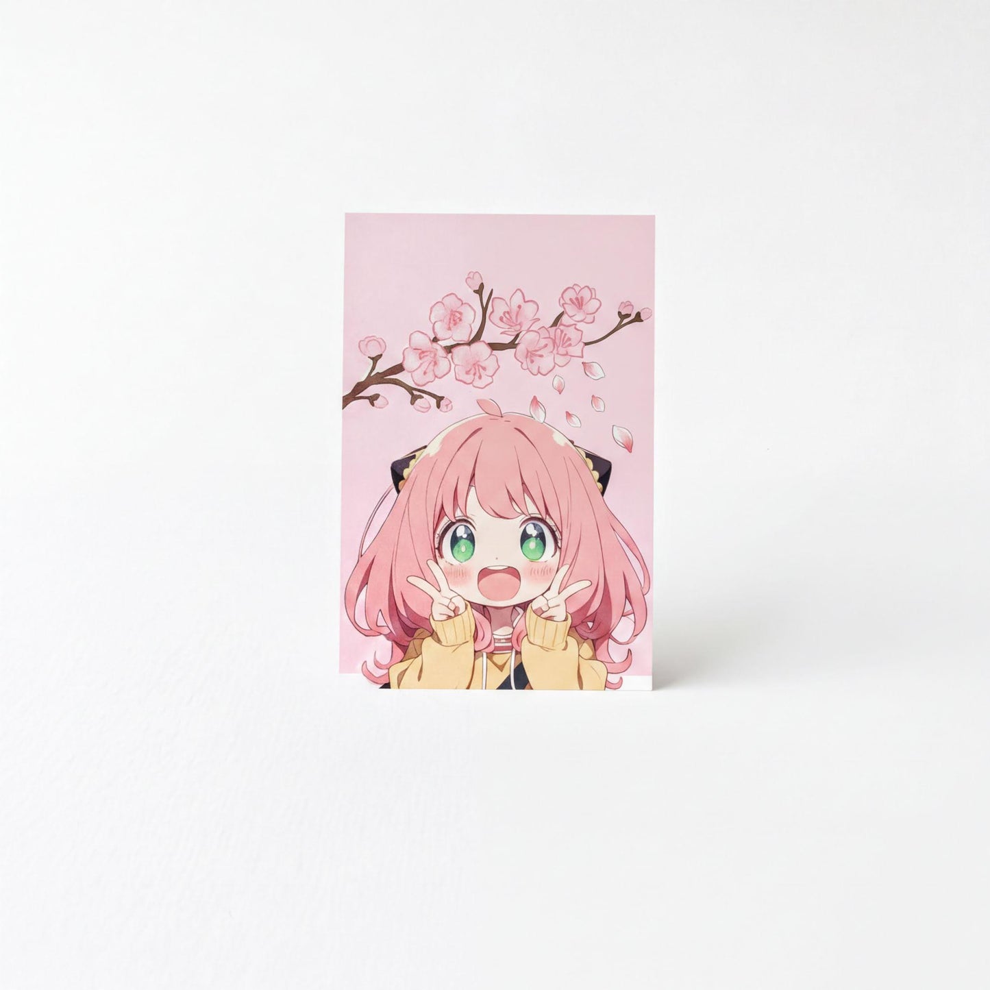 A pink card featuring an illustration of a young girl with pink hair and a yellow jacket, making a peace sign with her fingers.