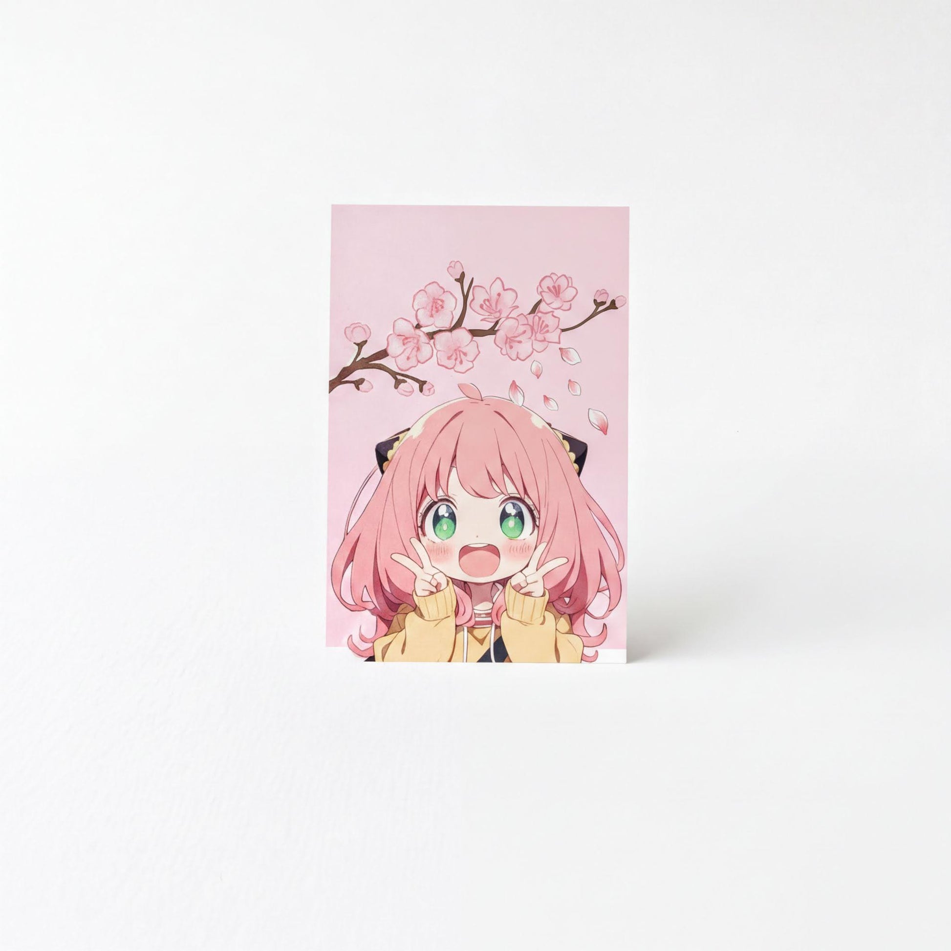 A pink card featuring an illustration of a young girl with pink hair and a yellow jacket, making a peace sign with her fingers.