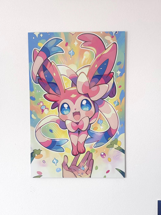 Tableau métallique en aluminium brillant représentant le Pokémon Nymphali sautant joyeusement de face au-dessus d'une main tendue, entouré d'une aura magique aux couleurs pastel rose, bleu et jaune avec des étoiles scintillantes.