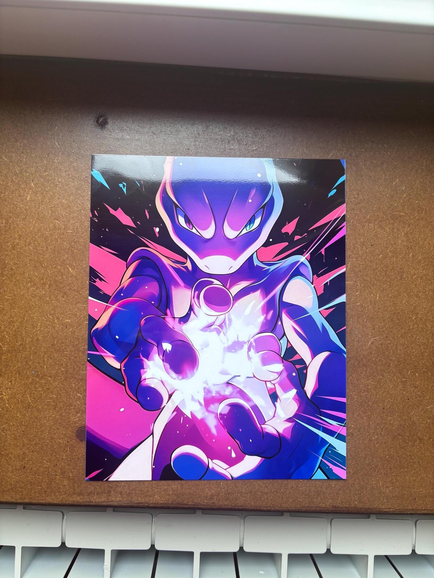 Peut inclure: Une impression d'art rectangulaire représentant une créature stylisée violette et bleue aux yeux brillants, tendant les mains vers l'avant pour générer une explosion d'énergie blanche et crépitante sur un fond rose vif et bleu foncé.