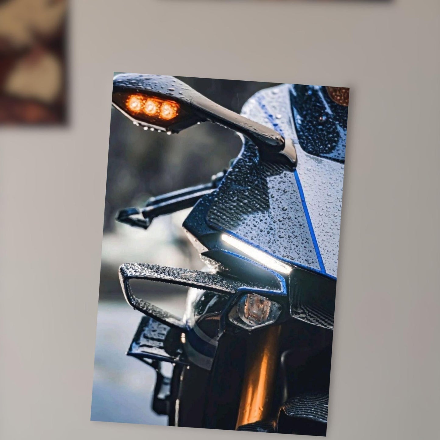 A close-up photograph of a motorcycle with a wet, shiny surface, featuring a red light on the handlebar and a reflective surface on the body.