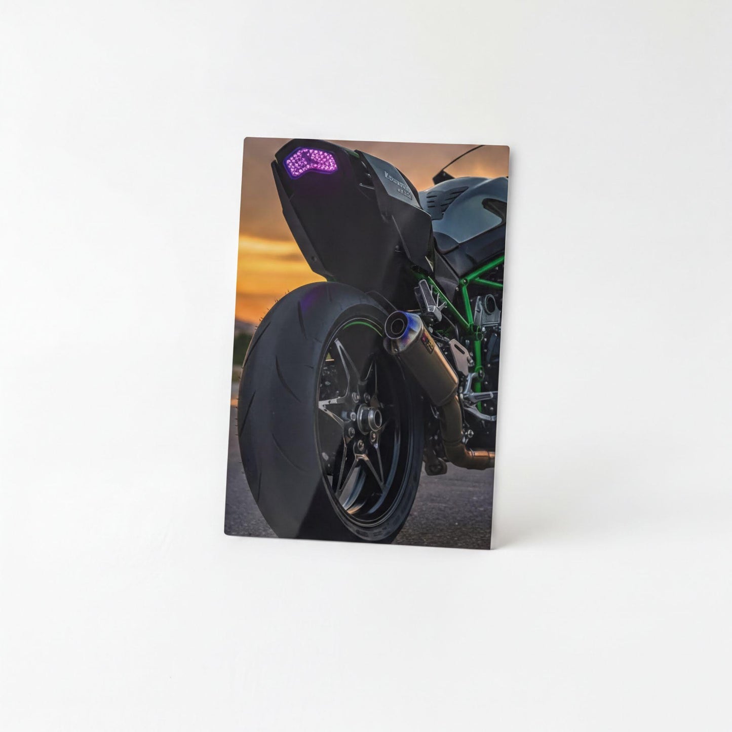 A close-up view of a motorcycle's rear tire and exhaust pipe, with a colorful LED light on the back of the motorcycle.
